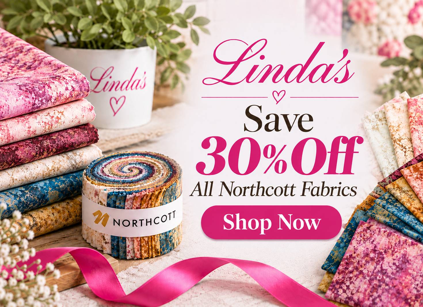 A bright, softly lit fabric display is arranged in a wide, front-facing composition, with stacks of pink, cream, blue, and patterned folded fabrics, a...